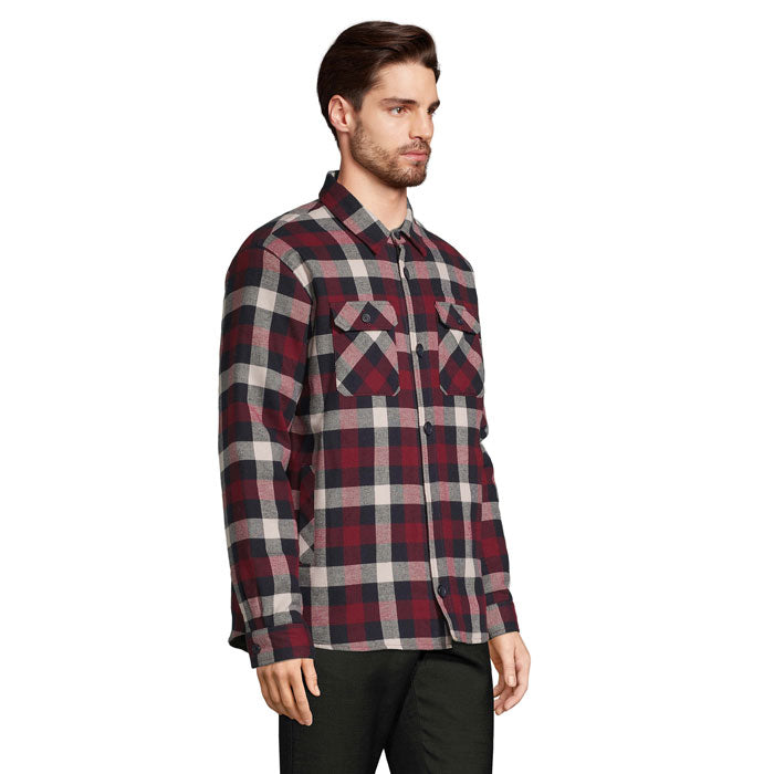 Vista lateral de hombre con sobrecamisa de cuadros rojos y oscuros