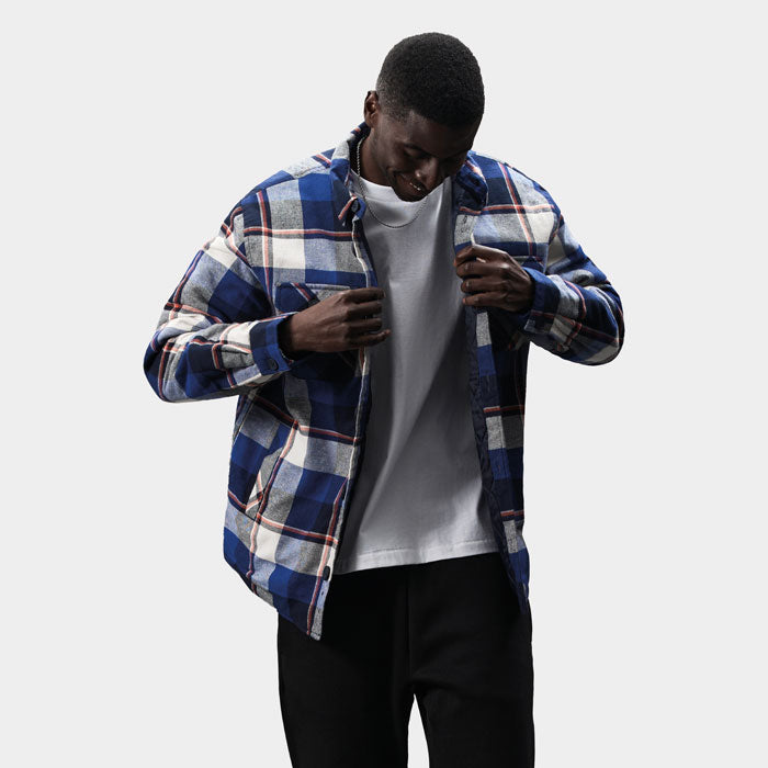 Modelo abriendo una sobrecamisa de cuadros azules para mostrar el forro interior