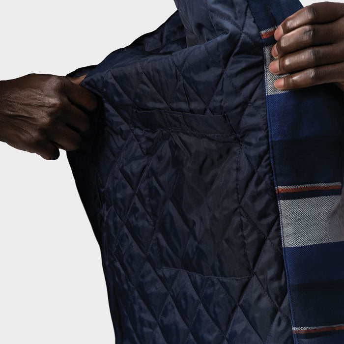 Detalle del interior acolchado oscuro de una sobrecamisa de cuadros