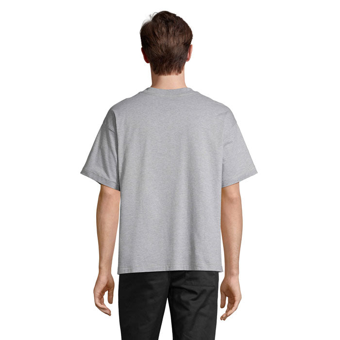 Vista trasera de camiseta oversize en color gris, con corte amplio y hombros caídos, ideal para un estilo casual.