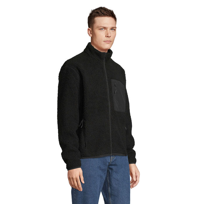 Vista lateral de hombre con chaqueta sherpa negra y pantalón vaquero
