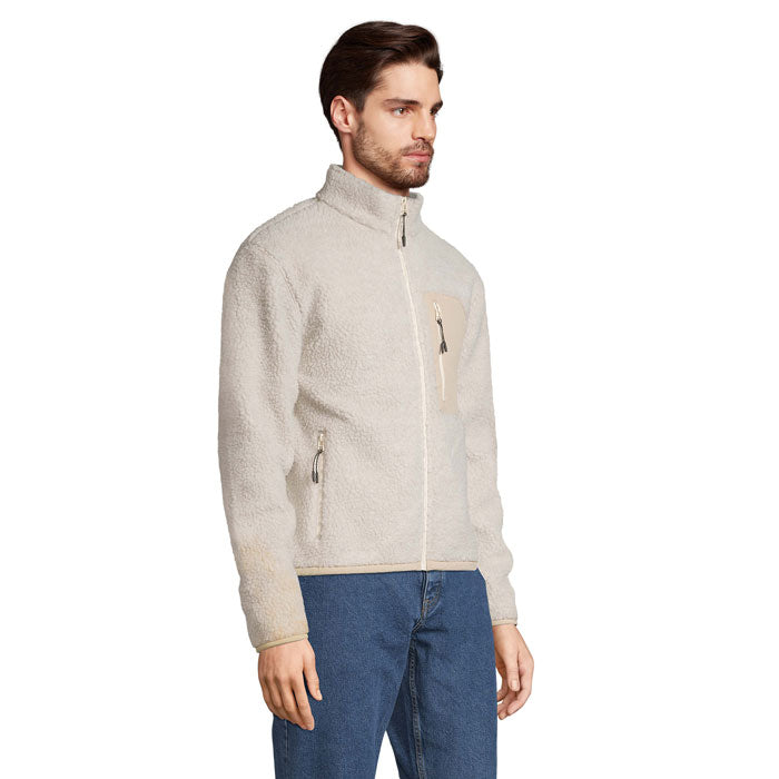 Vista lateral de hombre con chaqueta sherpa beige y pantalón vaquero