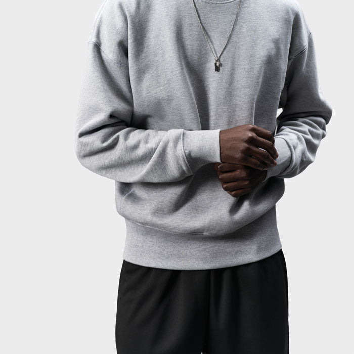 Detalle frontal de sudadera gris claro con mangas amplias y puños acanalados