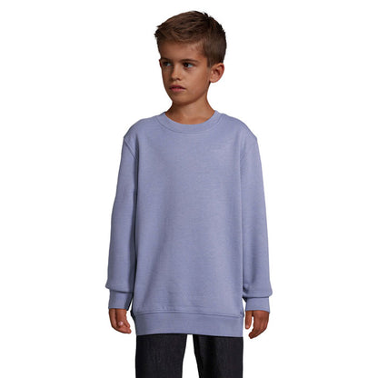 Imagen frontal de niño con sudadera lila lisa y pantalón vaquero.