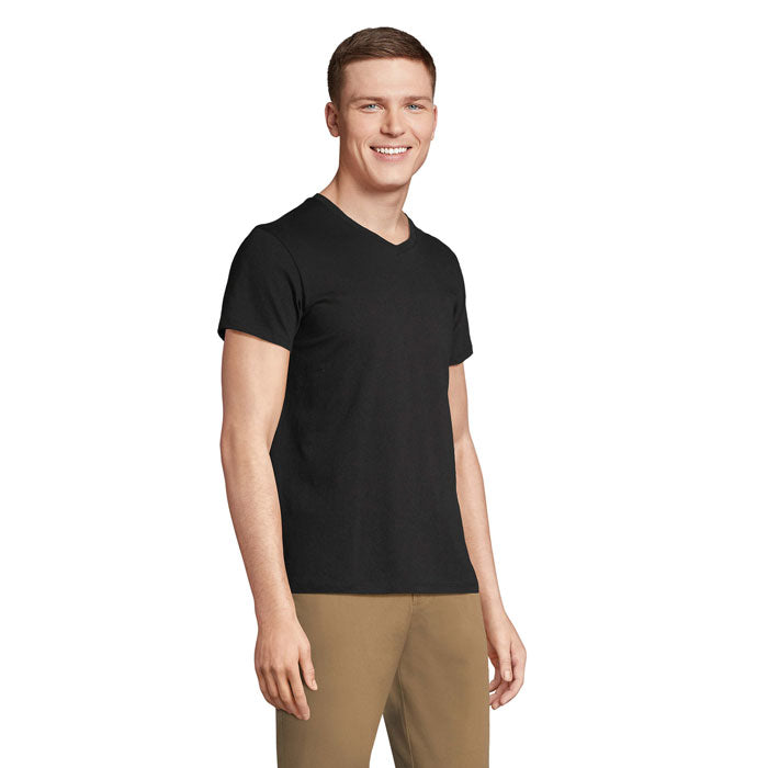Modelo sonriendo con camiseta negra de cuello en V, 100% algodón, vista lateral, ideal para uso diario.