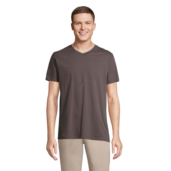 Hombre sonriente con camiseta gris de cuello en V, fabricada en 100% algodón, vista frontal.