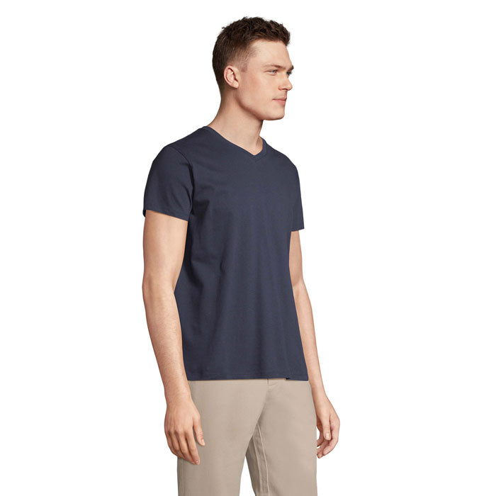 Modelo masculino con camiseta de cuello en V color azul marino, vista lateral, con un diseño moderno y corte tubular.