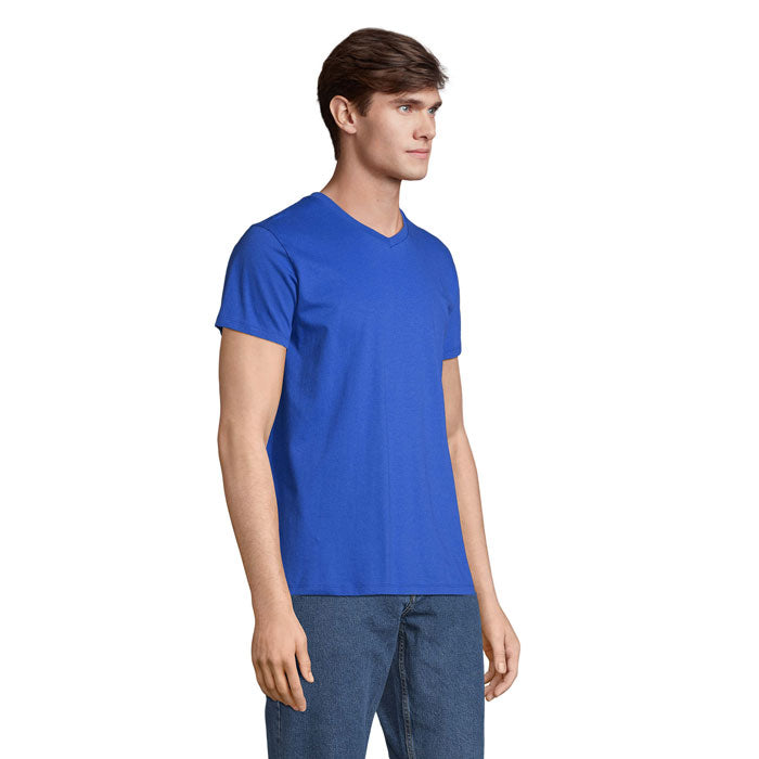 Modelo con camiseta azul, cuello en V, fabricada en algodón, vista lateral en ambiente natural.
