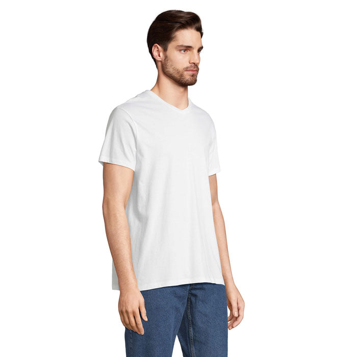Modelo masculino usando camiseta de algodón blanca con cuello en V, vista lateral, ideal para looks casuales.