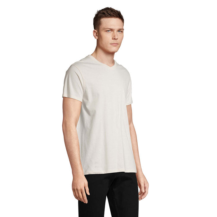 Modelo masculino vistiendo camiseta de algodón color claro con cuello en V, vista lateral.
