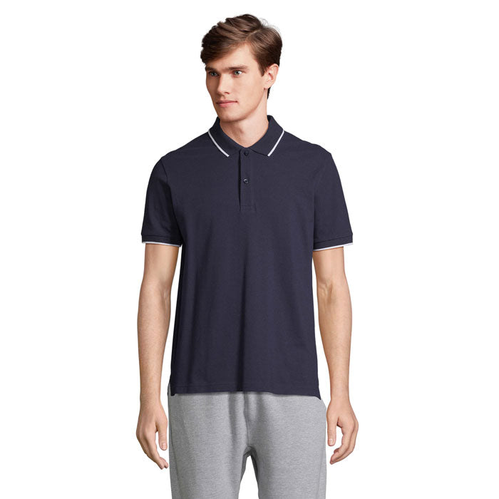 Hombre con camiseta polo PALERMO, color oscuro, visible ribete en el cuello y mangas. Corte cómodo y ajuste casual.
