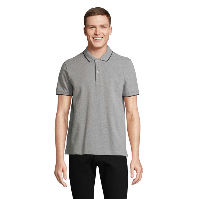 Modelo sonriente vistiendo la PALERMO CAMISETA POLO en gris claro con detalles de contraste.