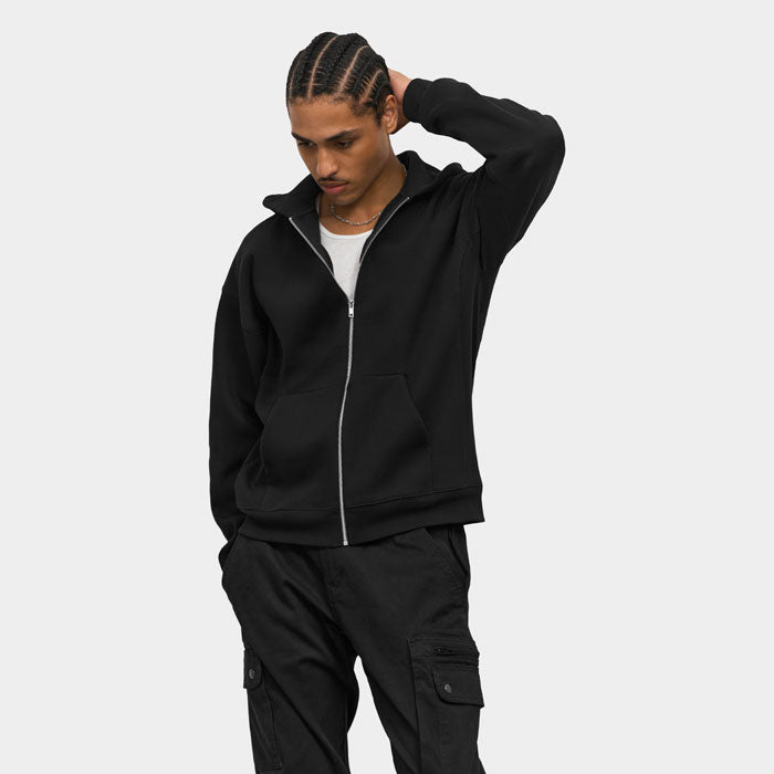 Modelo con sudadera negra y capucha, con una mano detrás de la cabeza