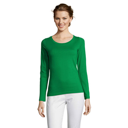 Mujer de frente con camiseta verde ajustada y pantalón blanco