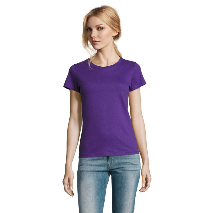 Mujer usando camiseta de color púrpura con cuello redondo y mangas cortas, combinada con jeans.