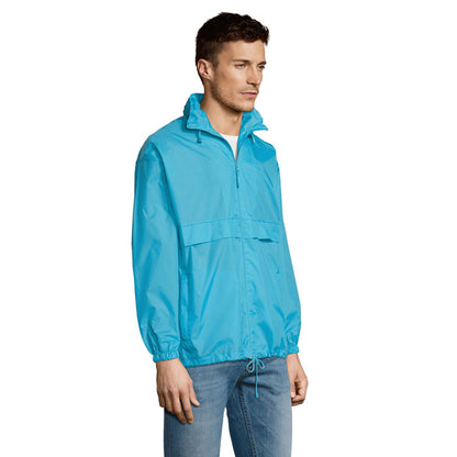 Modelo masculino de lado con cortavientos azul y puños elásticos.