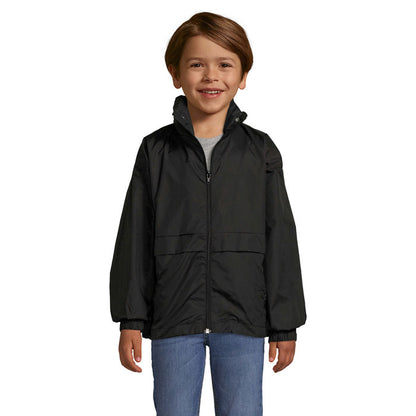 Niño con chaqueta impermeable negra con cremallera y capucha, vista frontal.